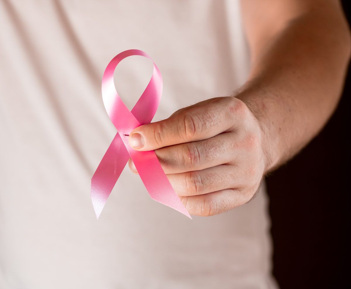 Hands holding a pink breast cancer awareness ribbon