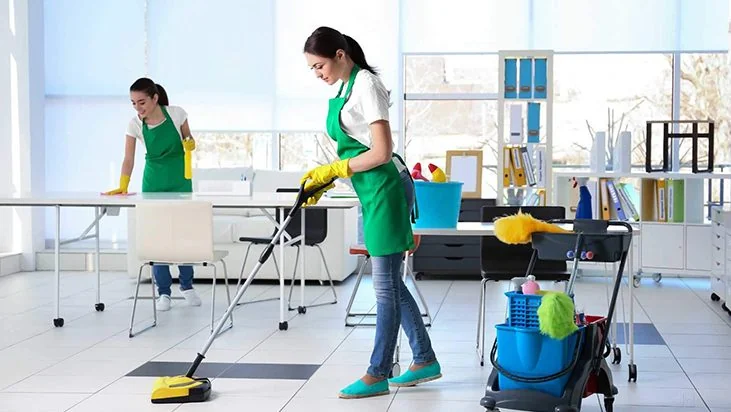 Two cleaners tidying an open-plan office