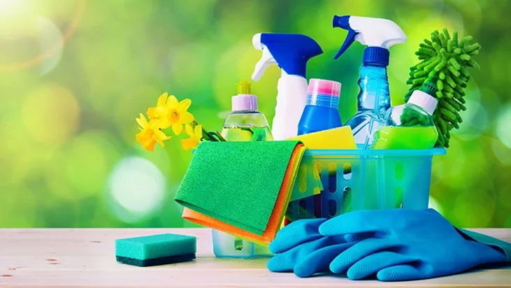 Spray bottles, cloths, sponges, and gloves in a cleaning caddy